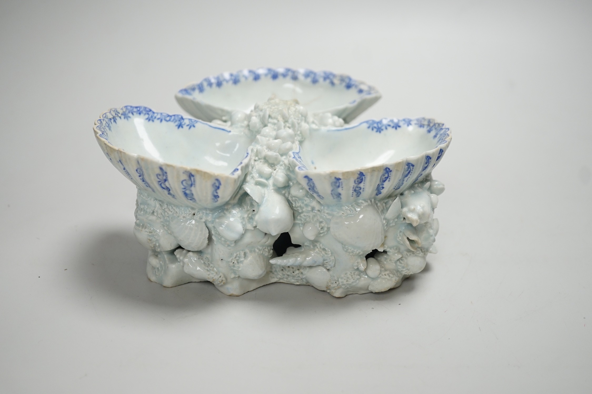 An early Bow porcelain three shell salt, the naturalistically modelled shells picked out in underglaze blue, on a shell and coral encrusted base, 8cm high